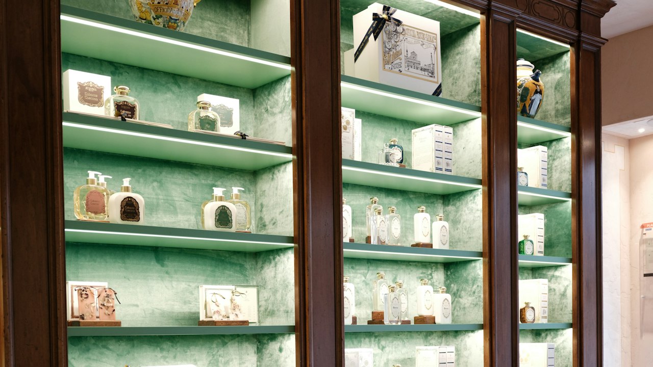 A perfumery counter with dark wood cabinetry and glass shelves under warm light